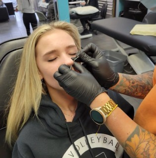 George piercing a client at Strange World Tattoo