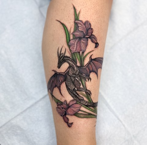 Full-colour dragon among purple irises on a calf, tattooed by Valeriia Mosina