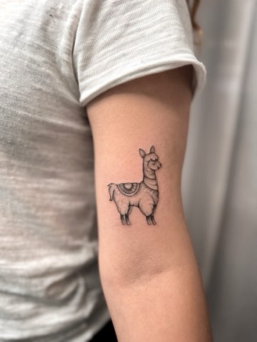 Small fine line llama tattoo on an upper arm by Valeriia Mosina
