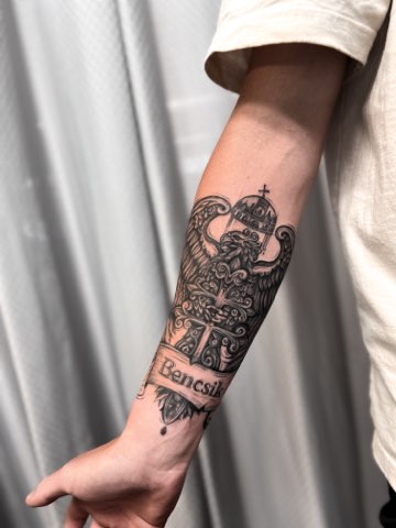 Black and grey heraldic crowned eagle and banner on a forearm by Valeriia Mosina