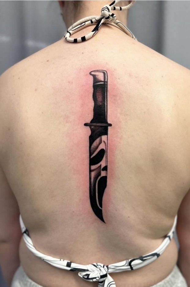 Black and grey Ghostface dagger tattooed down the spine by Abi Rojas