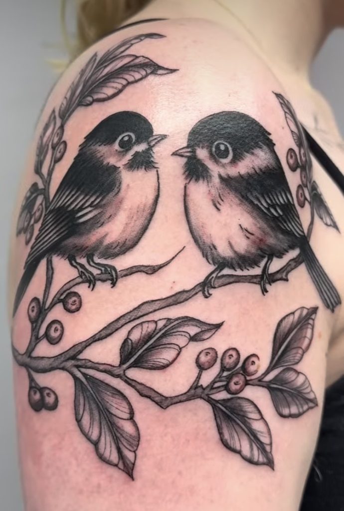 Black and grey pair of birds on a berry branch, tattooed on a shoulder by Abi Rojas