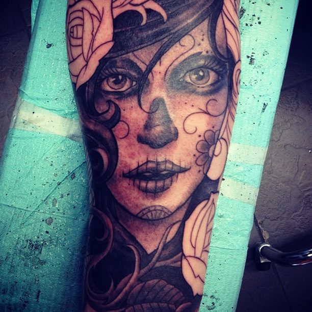 Black and grey Day of the Dead portrait with roses, tattooed on a forearm by Brett Schwindt